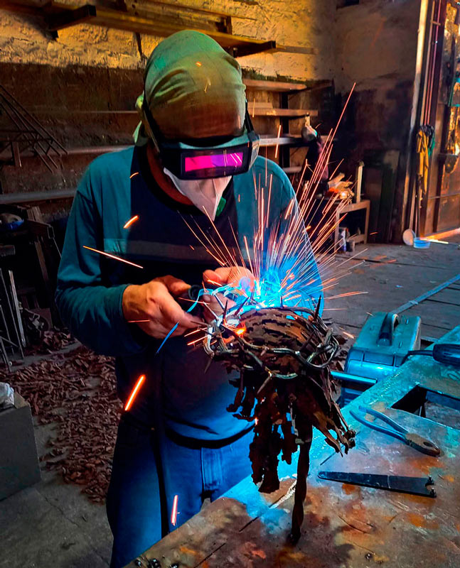 L’artista al lavoro. Selezionando schegge di forma speciale, crea i capelli sulla testa della scultura di Cristo.